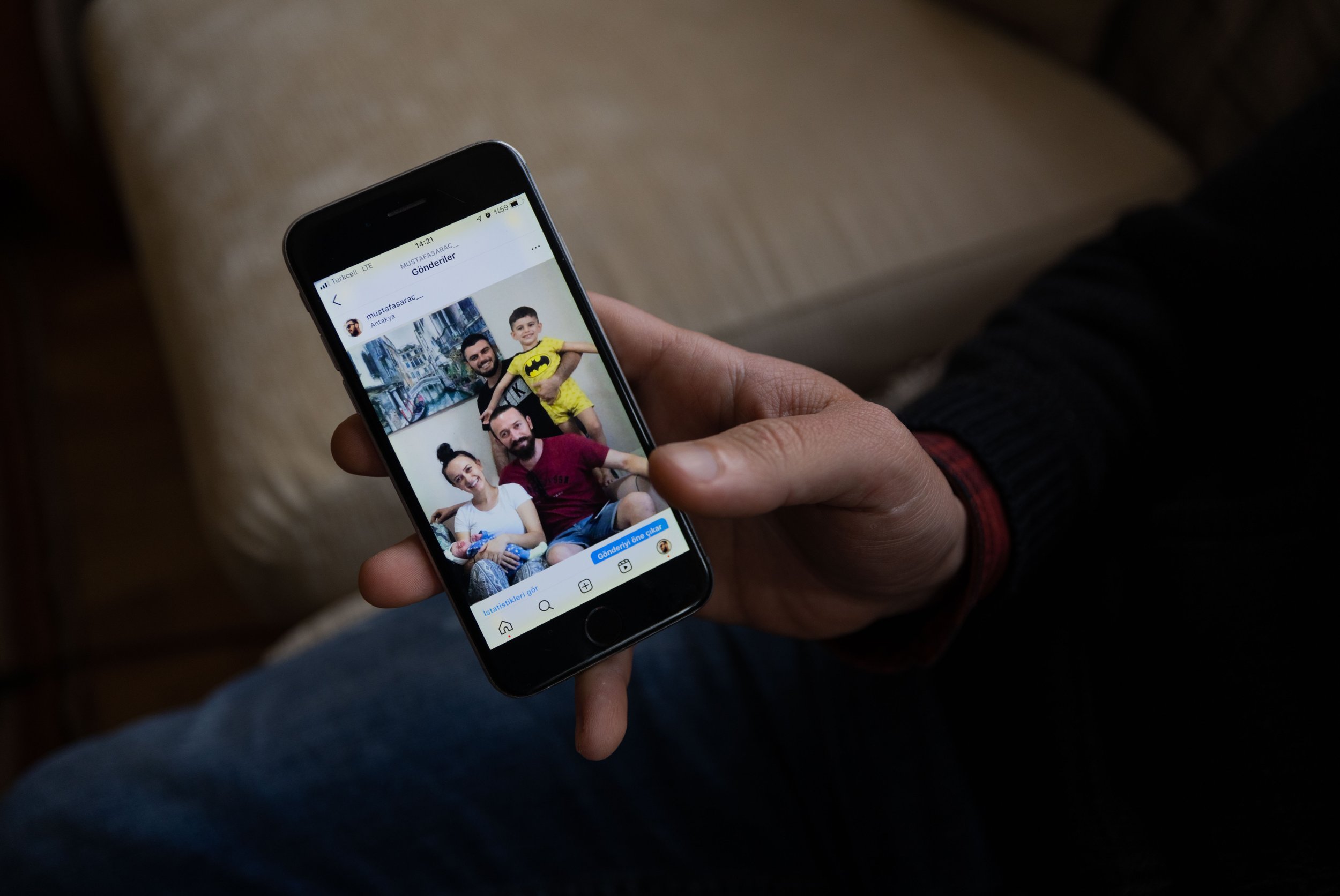 Mustafa holds a photo of himself with his sister, Zehra, and her family, Hikmet, Kaan, and Bilge.