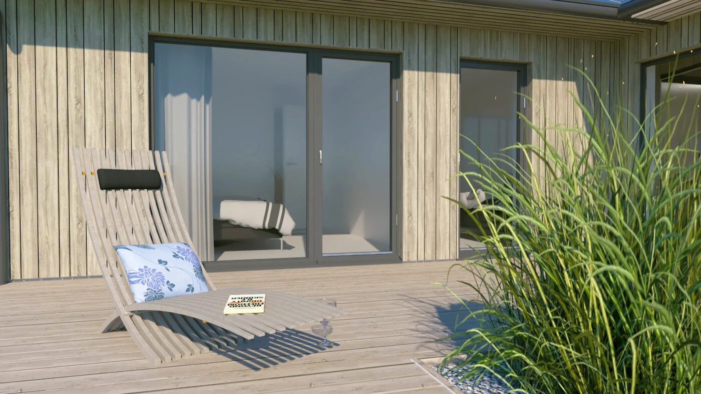 Terrass med en trästol, en kudde, en bok och ett vinglas, med ett hus i bakgrunden och gröna växter till höger.