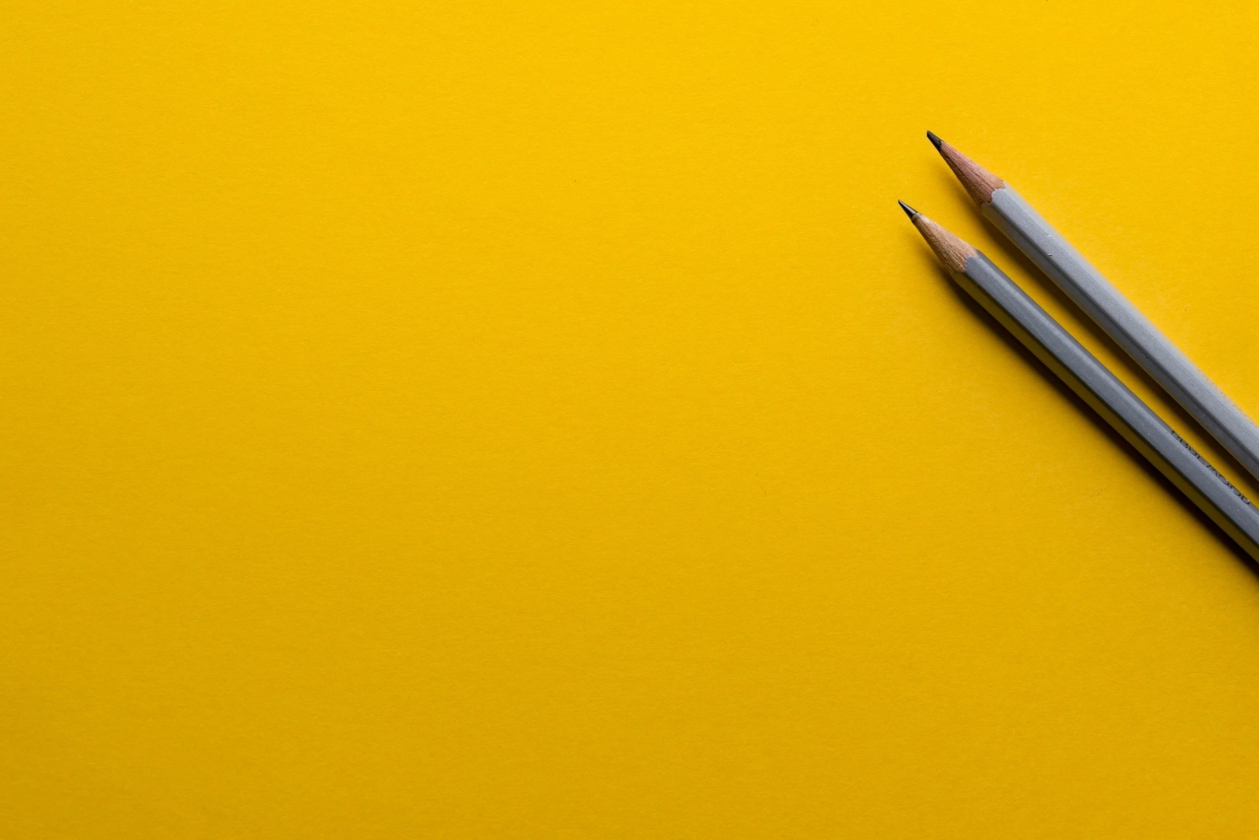 Two pencils on a yellow background.