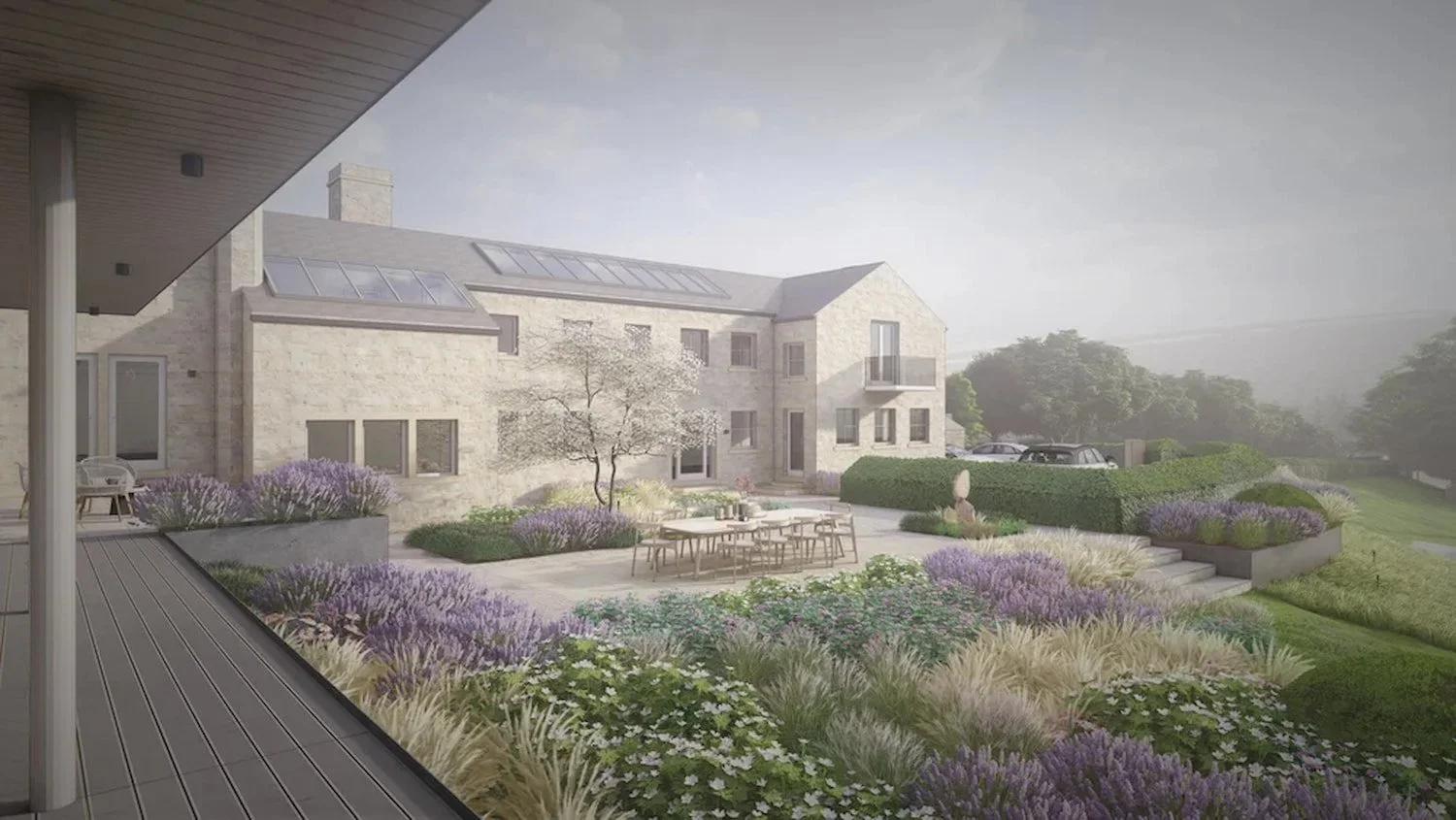 Modern country garden featuring a large stone patio with dining table, purple lavender borders and ornamental grasses