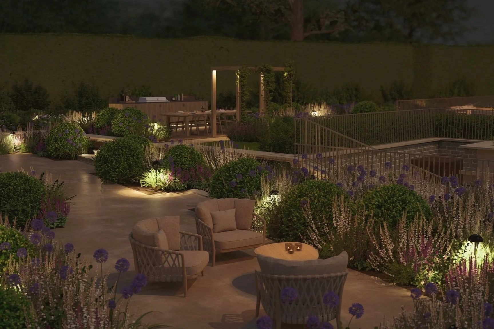 A beautifully lit outdoor garden patio at night with lush greenery, flowers, and seating areas including armchairs and small tables.