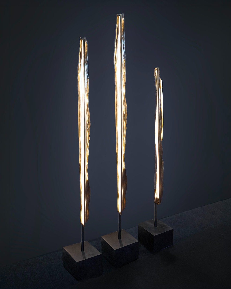 A vertical flame, held in stillness.

The THOR floor light from @cinabregallery is a study in quiet tension &mdash; where light meets reflection in a single, deliberate gesture. Its back is a darkly patinated bronze cast from tree bark, a raw imprint