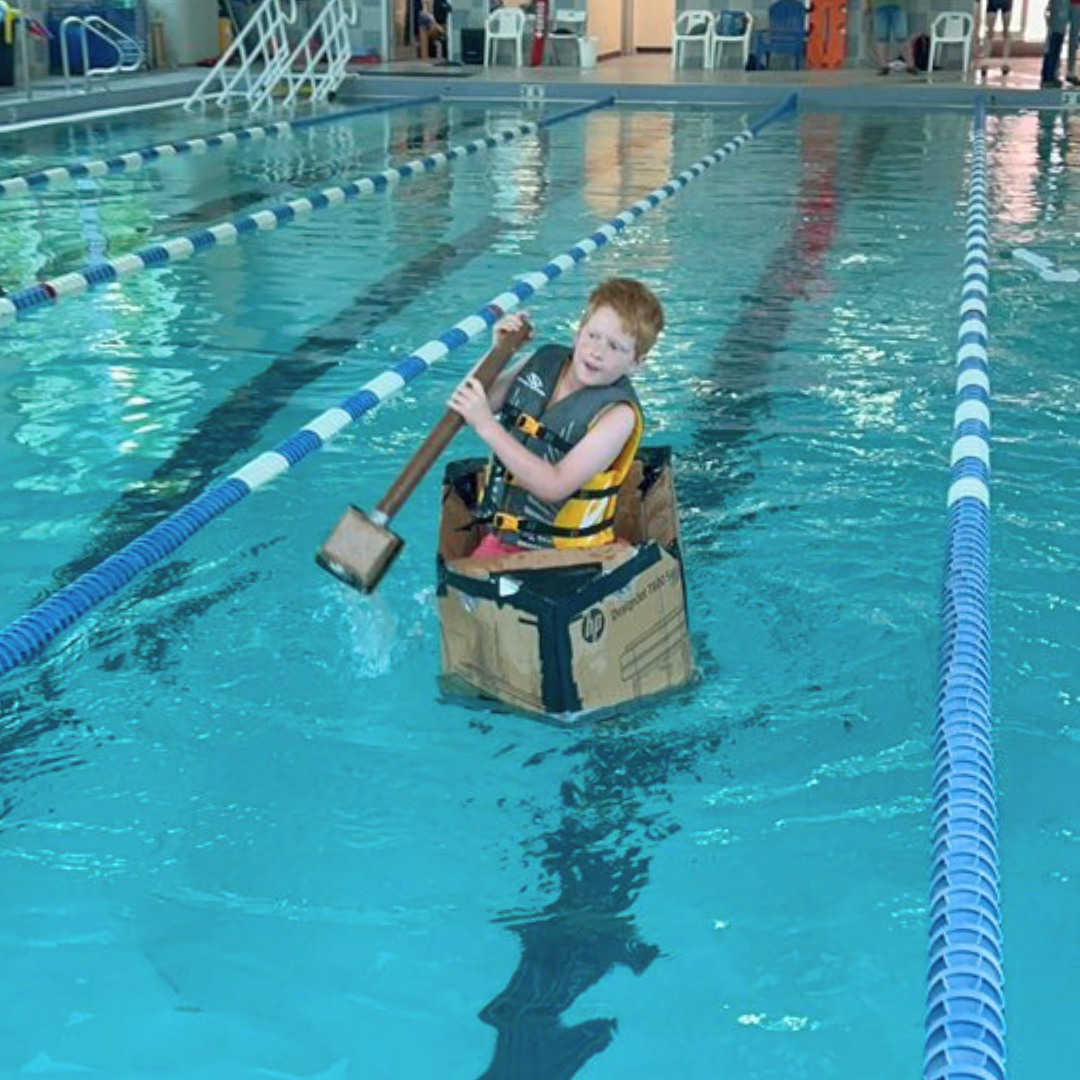 Cardboard yacht racing across the pool