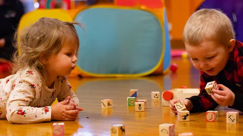 Two toddlers playing blocks together in the studio