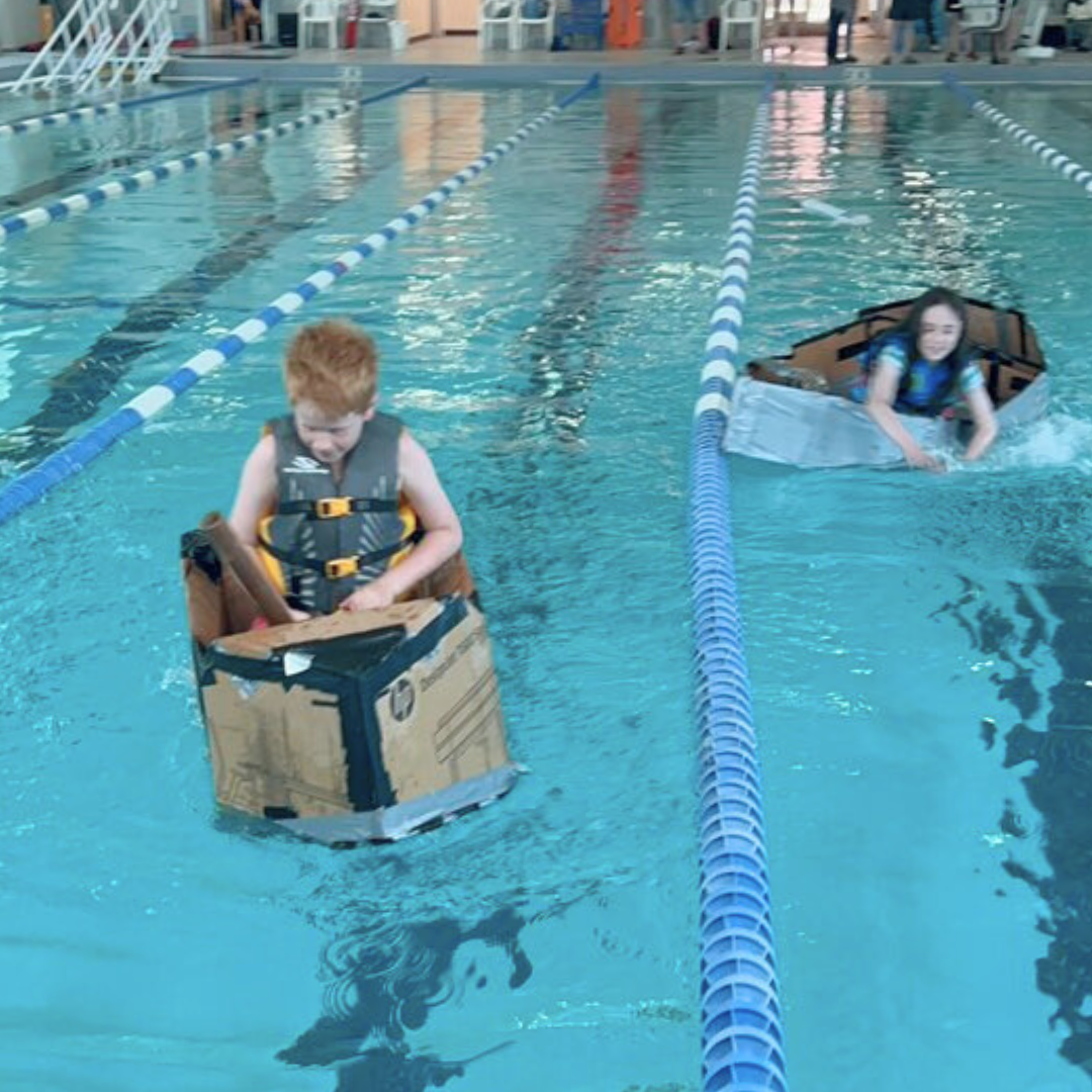 Children race their boats across the pool
