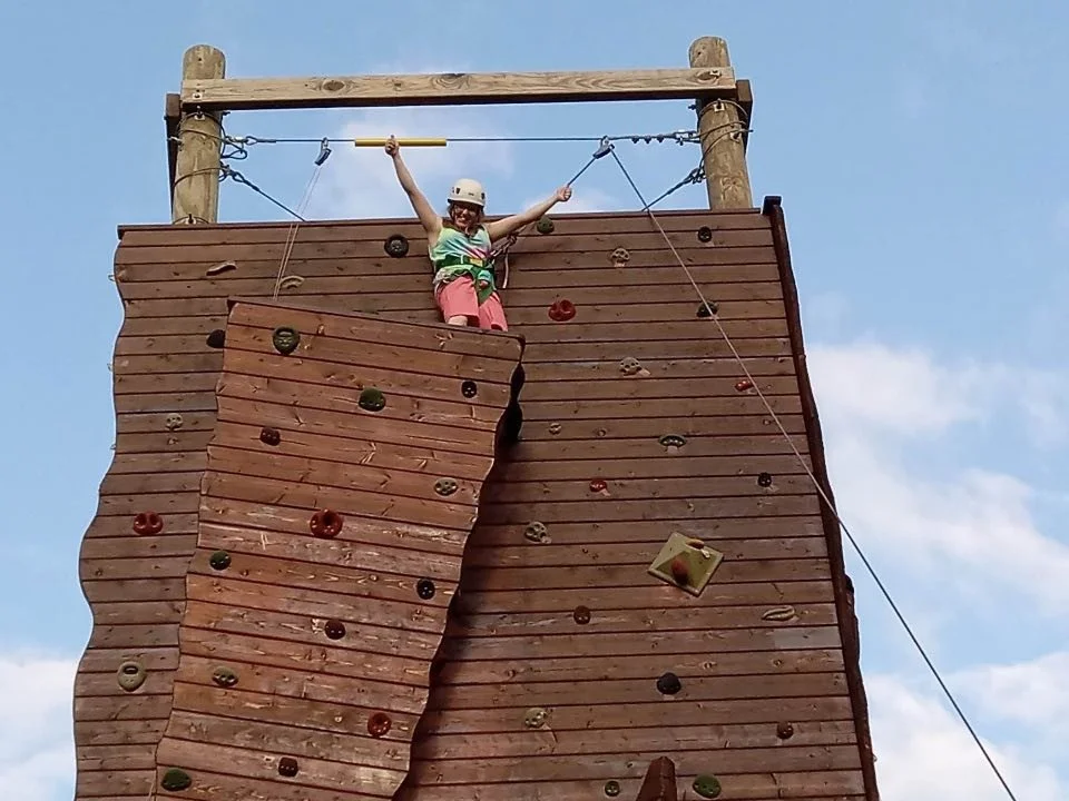 A climber celebrates reaching the top of the climbing tower