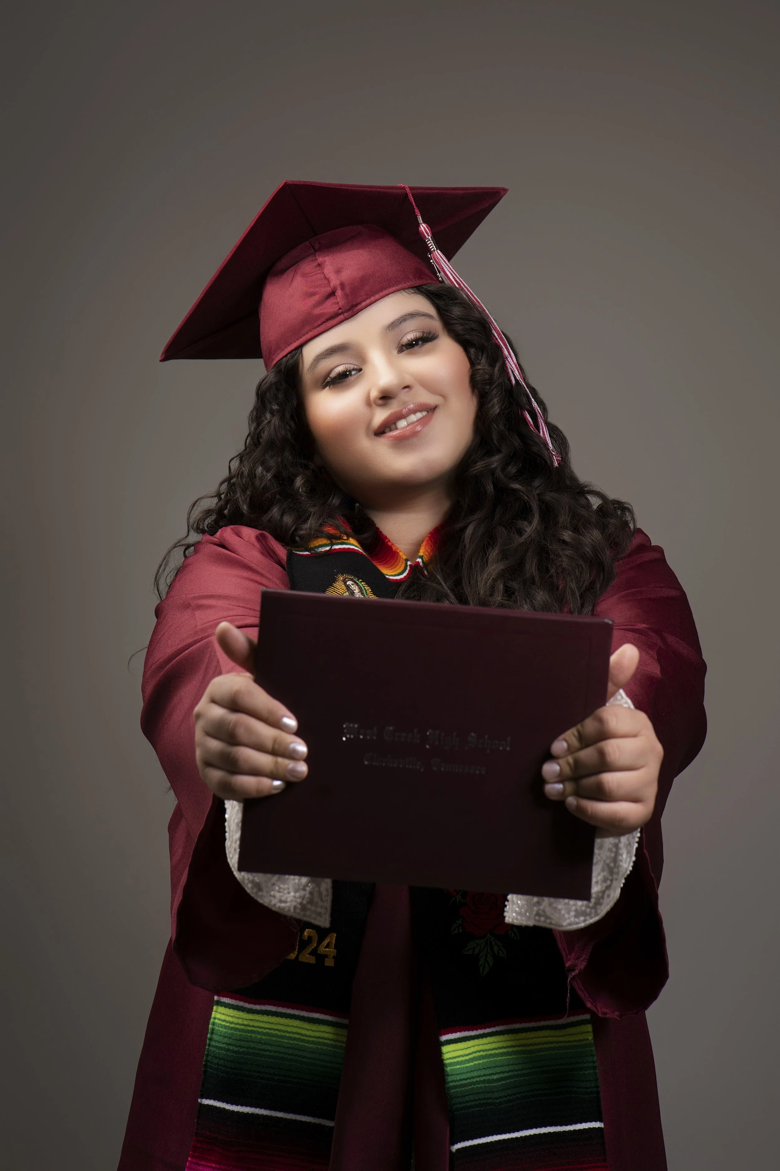 Graduate in maroon cap and gown holding diploma
