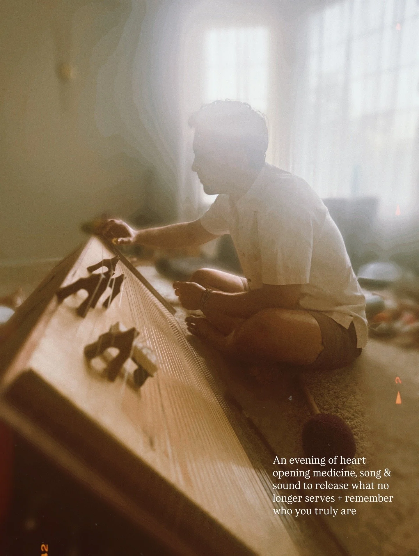 A person sitting cross-legged on the floor, playing an electronic musical instrument in a softly lit room with sheer curtains, with a quote about music and self-discovery overlaid on the image.