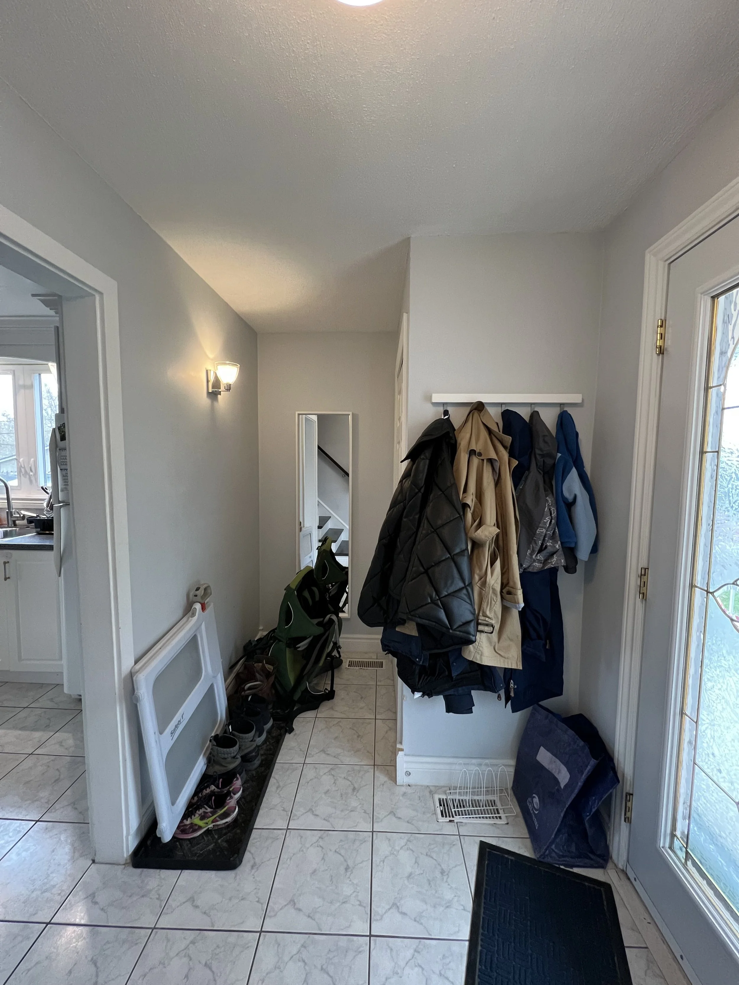 Entryway with coat hooks, jackets, shoes, and a door leading outside.