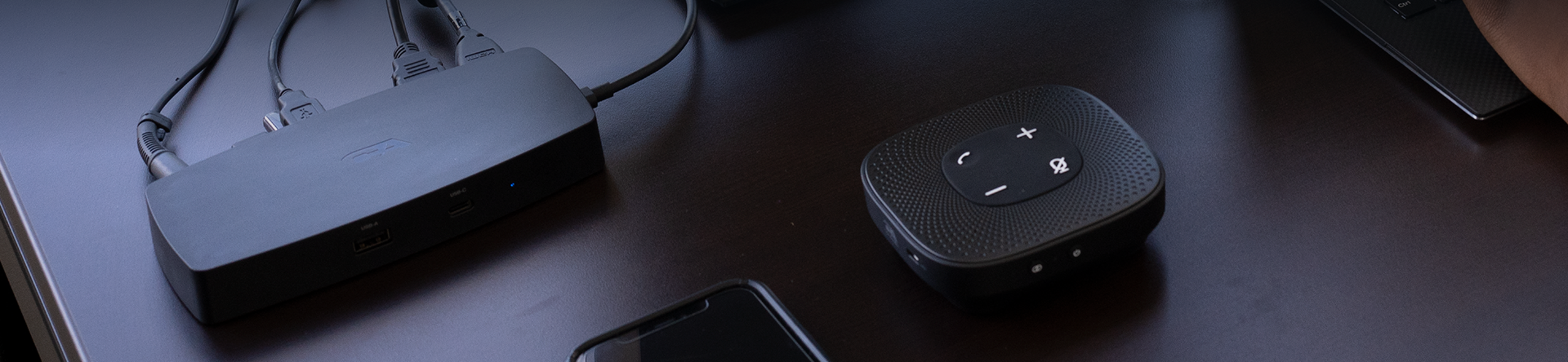Cyber Acoustics docking station and speakerphone on a dark wood desk