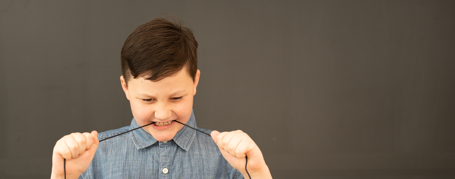 A young student chewing on a headset cord