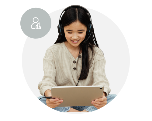 Young girl smiling and wearing school headphones, using a tablet device.