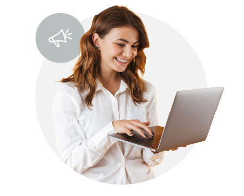A woman with shoulder-length hair, smiling and looking at a laptop.