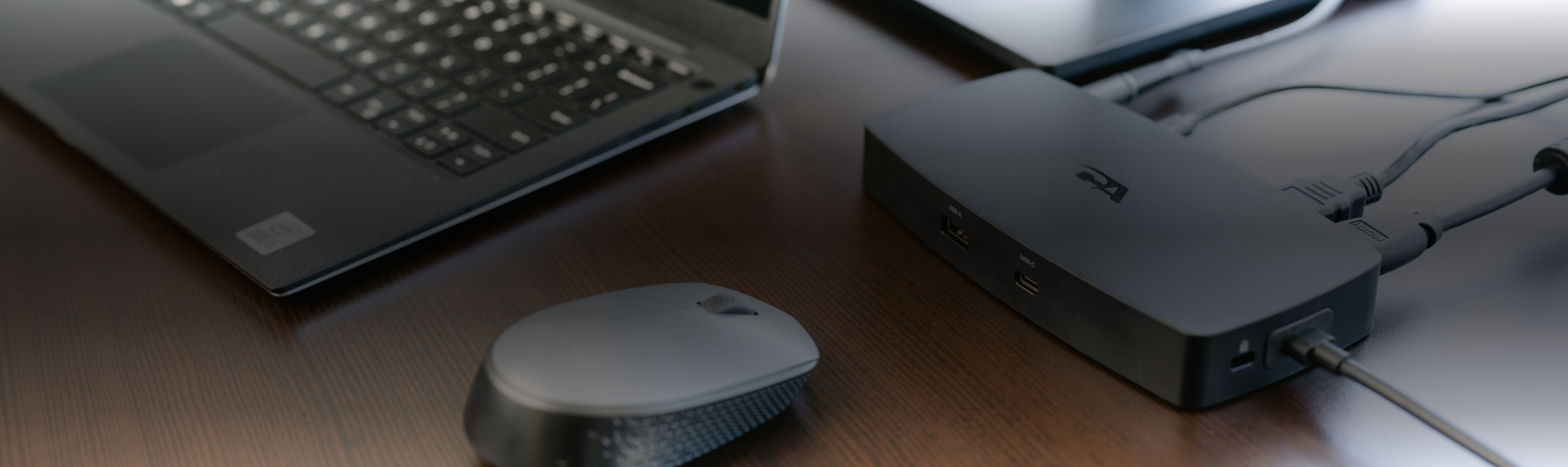 Laptop and wireless mouse connected to a Cyber Acoustics docking station on a desk