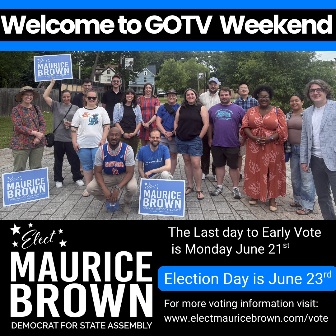 A group of people holding signs supporting Maurice Brown, a Democratic candidate, standing outdoors in a park with trees and houses in the background, during a campaign event.