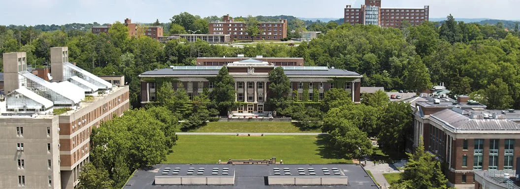 Aerial view of a university campus with green lawns, trees, and multiple school buildings.