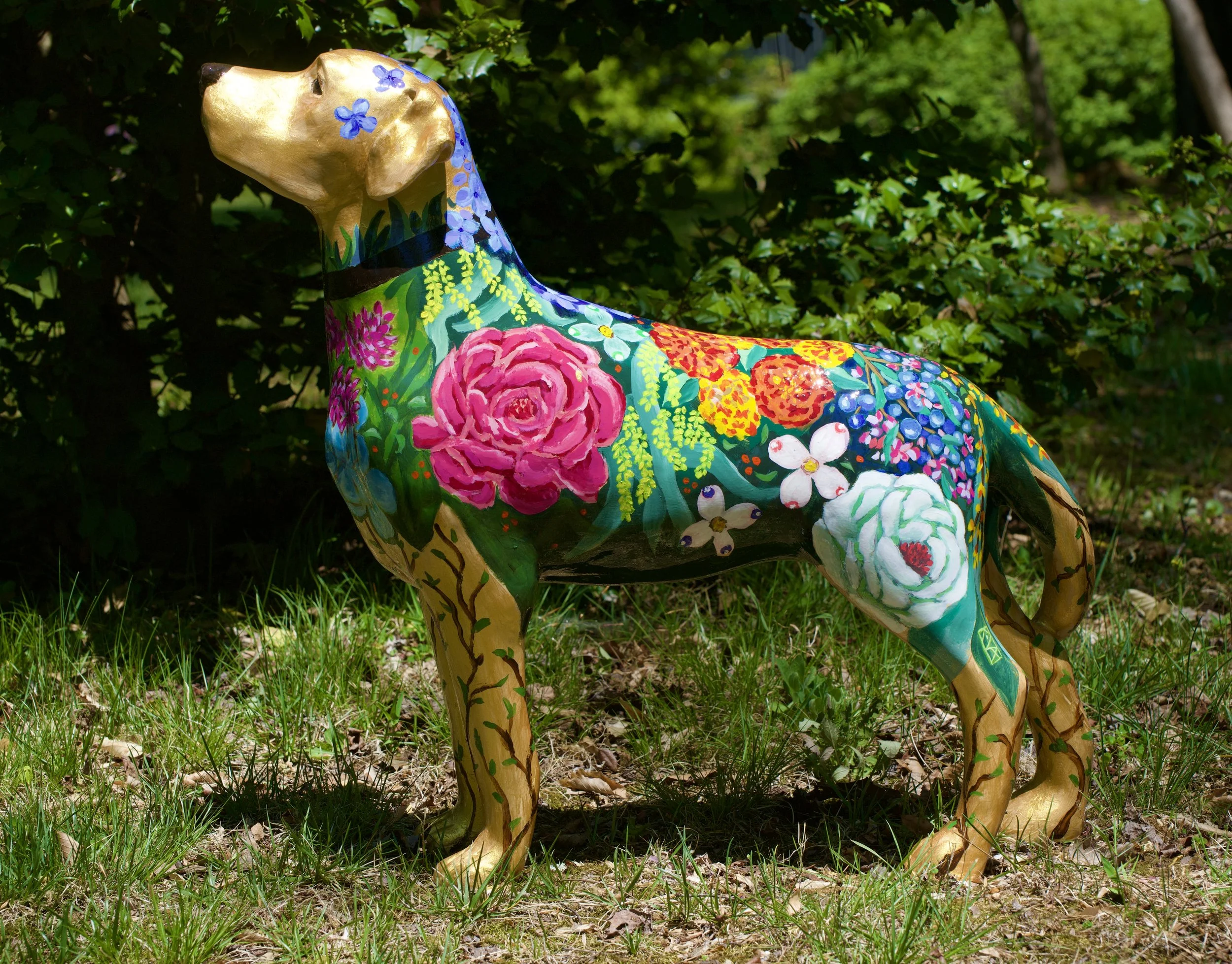 Colorfully painted horse sculpture outdoors among green foliage.