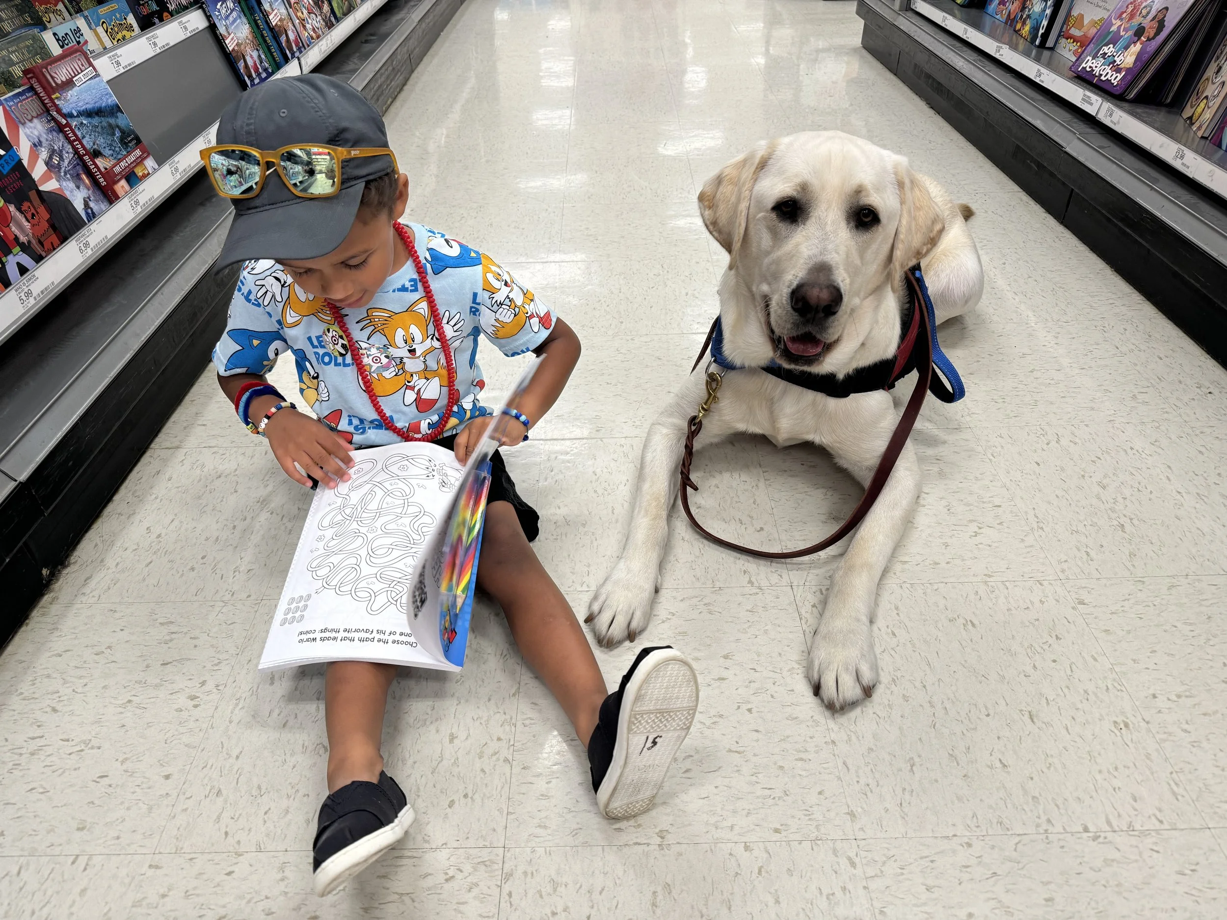 Child reading with autism service dog Finn in a store aisle
