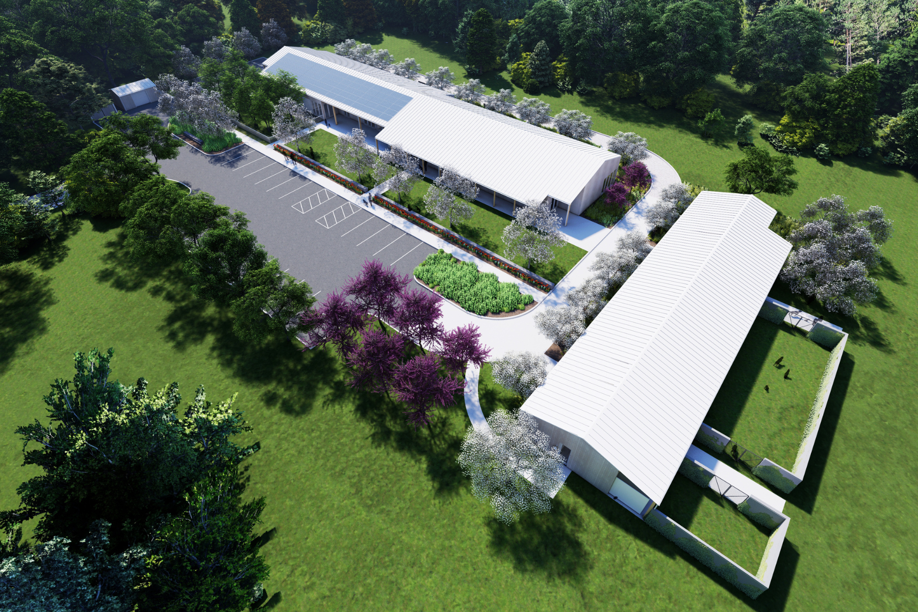 Aerial view of a modern building complex surrounded by landscaped gardens and trees with parking lot and green lawns.