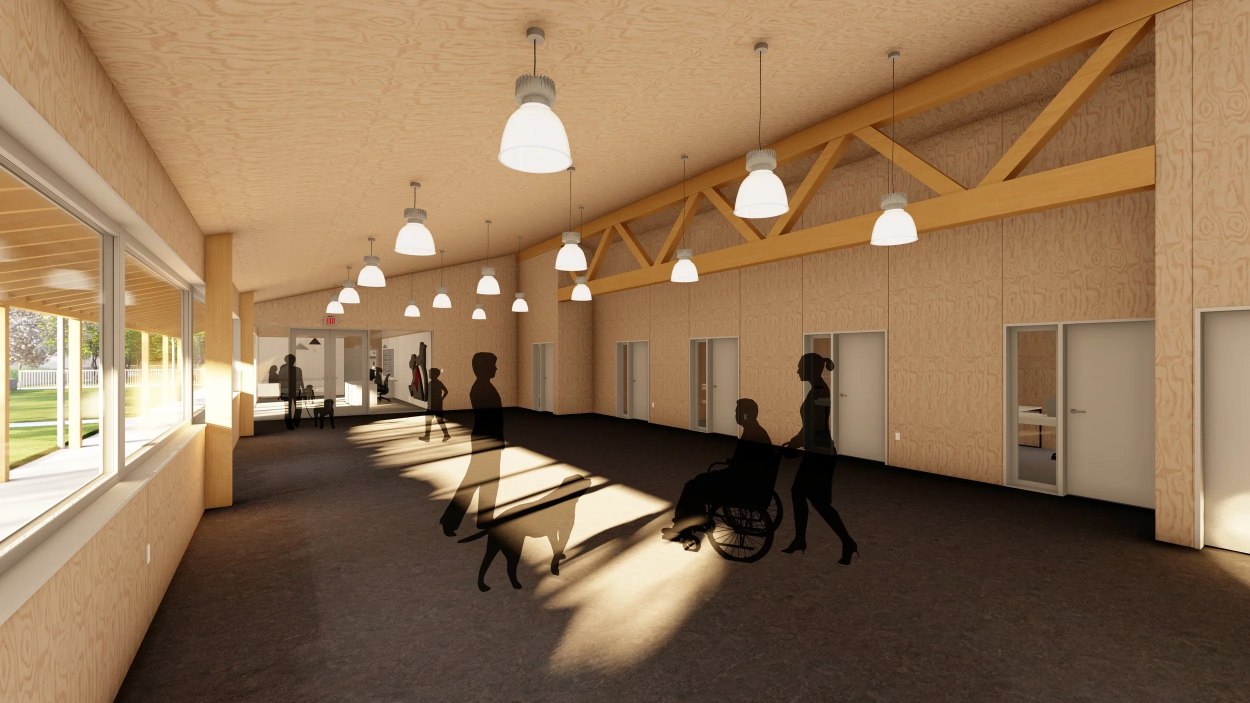 A spacious room with large windows on the left, wooden interior walls, and high ceiling with hanging lights. Shadows of people, including a person in a wheelchair, are cast on the floor. Several doors line the right wall, and outdoor greenery is visible through the windows.