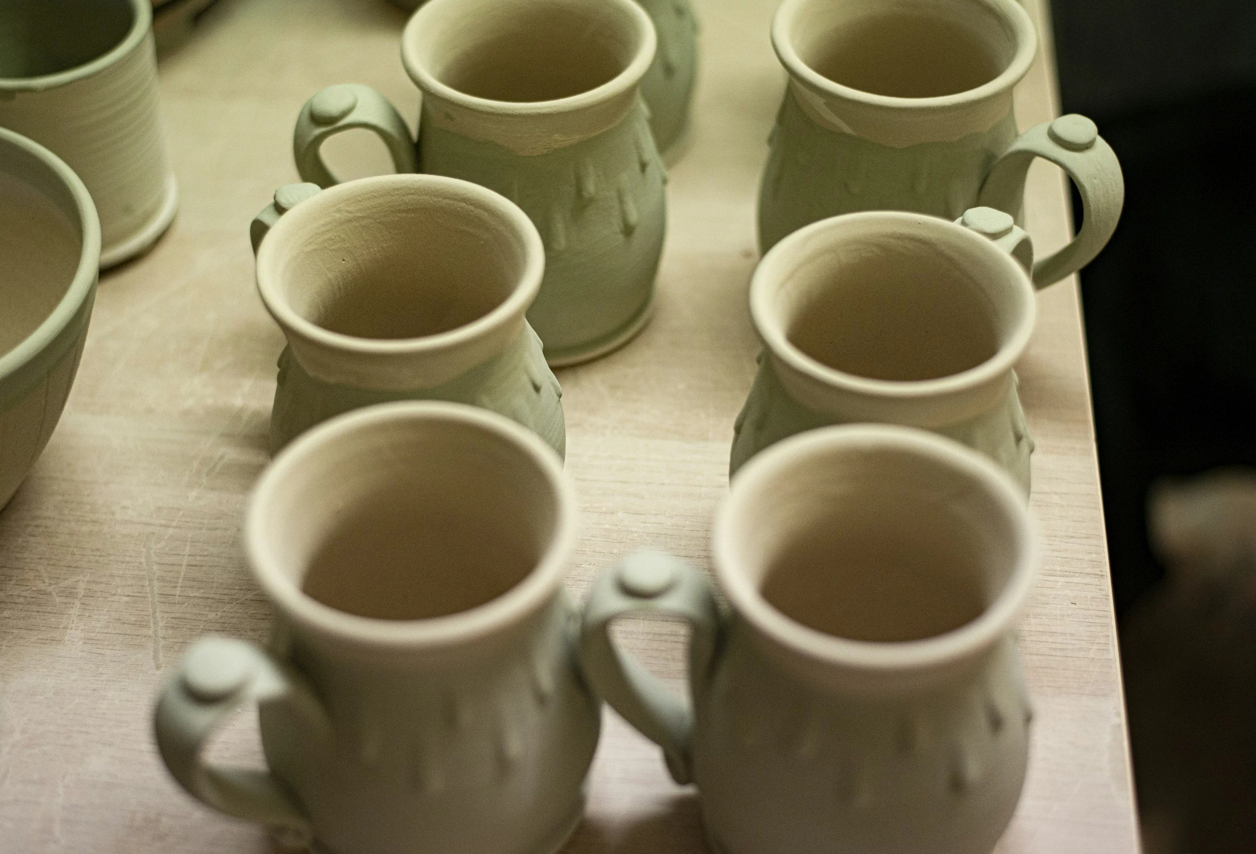 Rows of glazed mugs are ready to be fired.