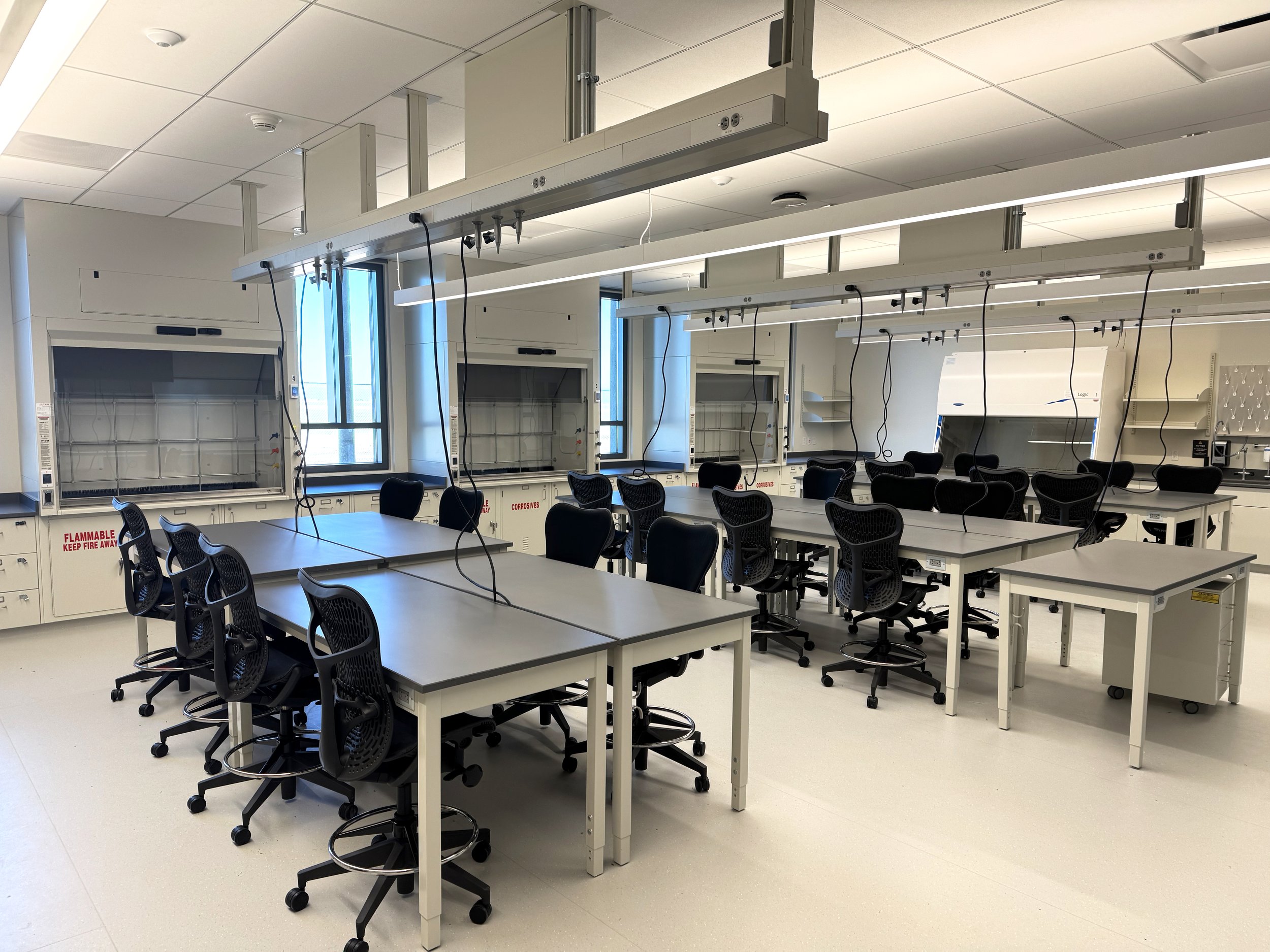 Tables with chairs pushed in and fume hoods, in a lab