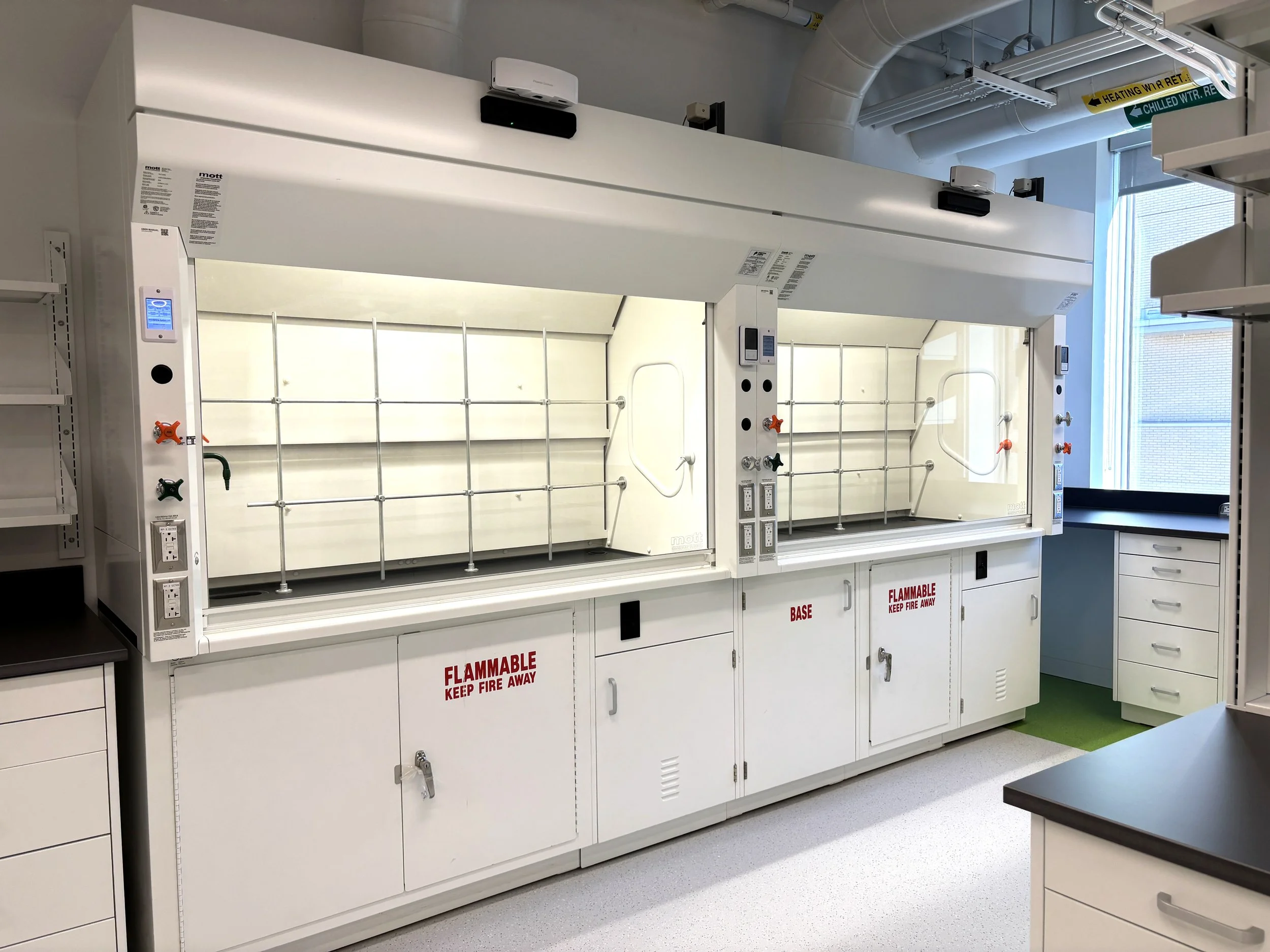 SafeGuard fume hoods with acid and flammable cabinets below, in a lab