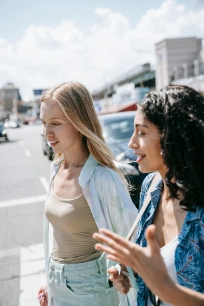 Two women talk while crossing a street