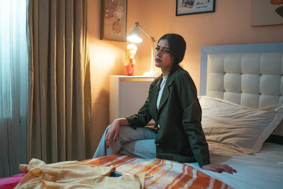contemplative-woman-sitting-on-bed-in-soft-light