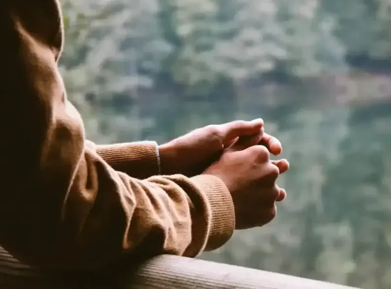 Close up of person leaning on a rail with hands together