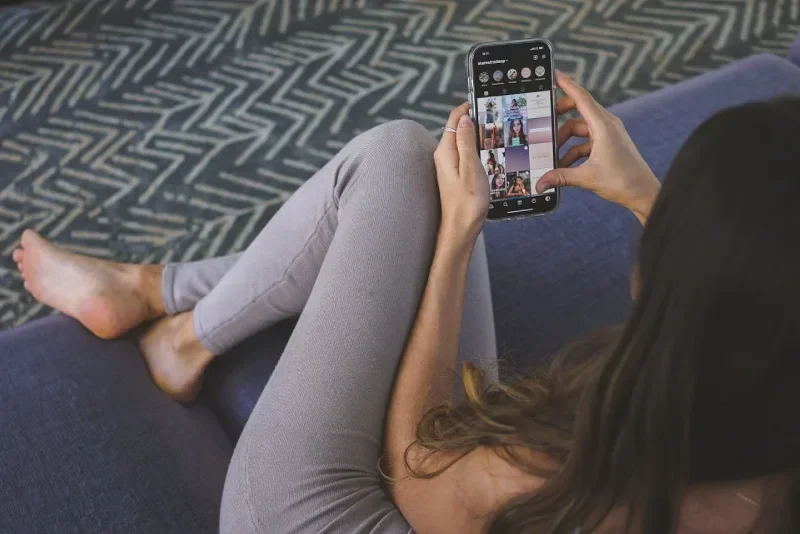 Woman sitting on coach looking at social media on phone