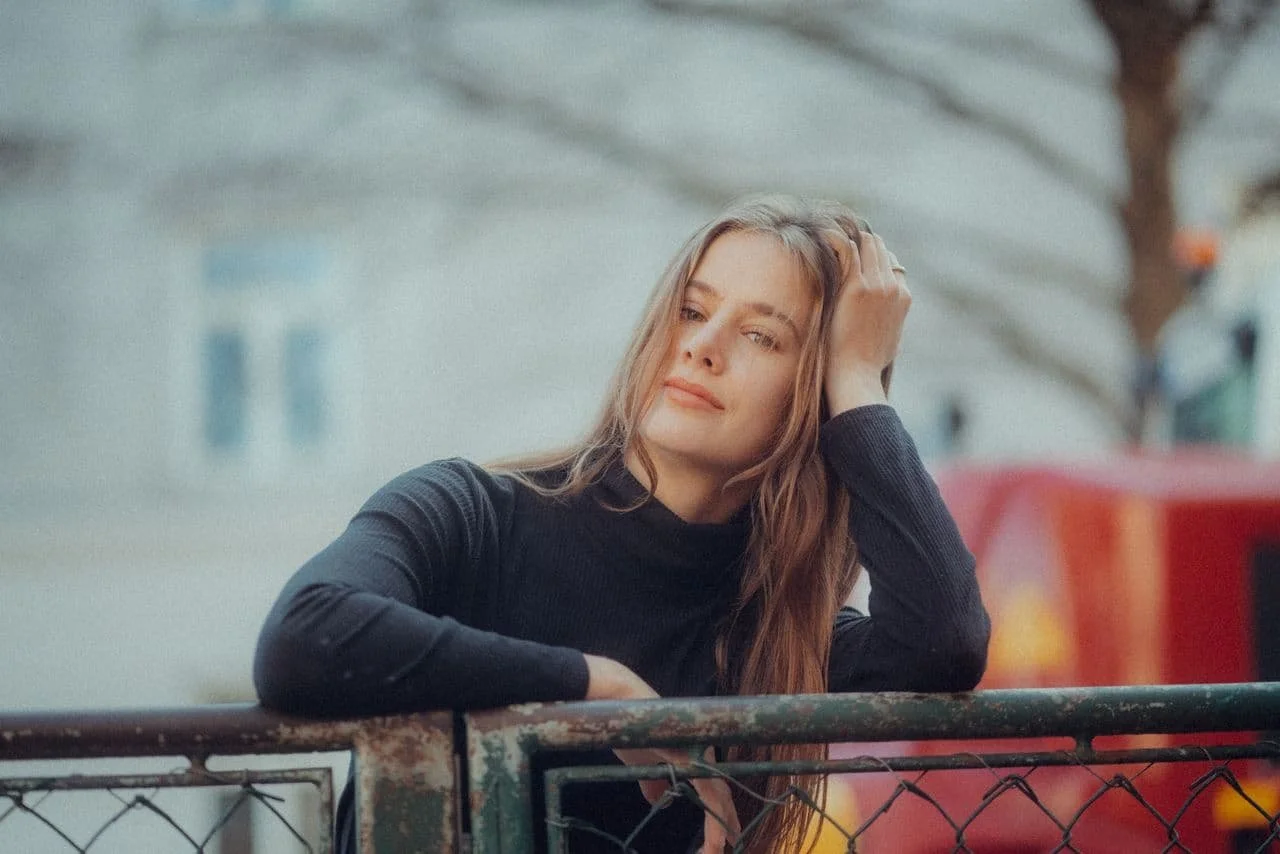 young-woman-in-a-black-turtleneck-leaning-against-a-fence