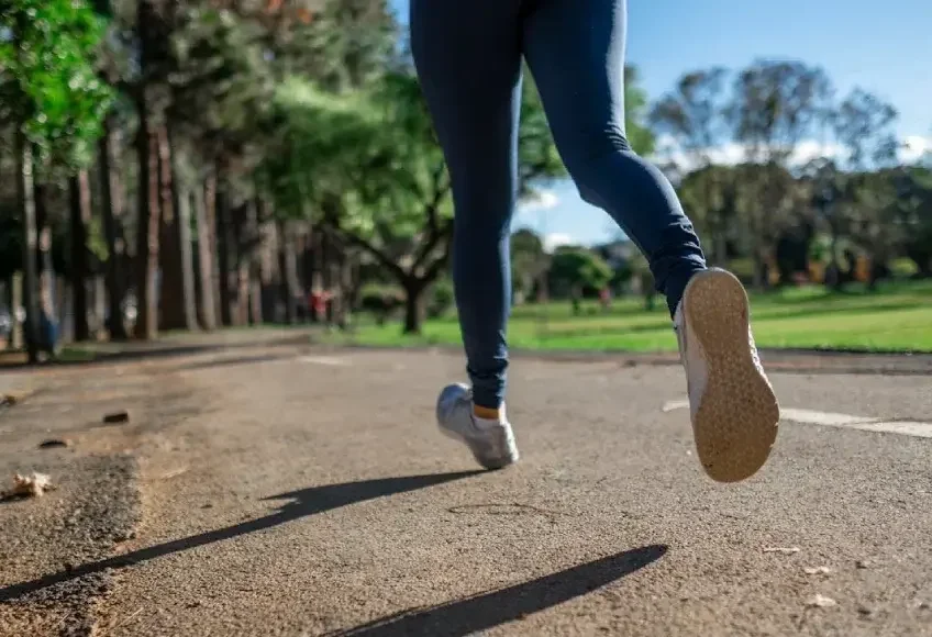 Close up of legs of a person jogging on a park path