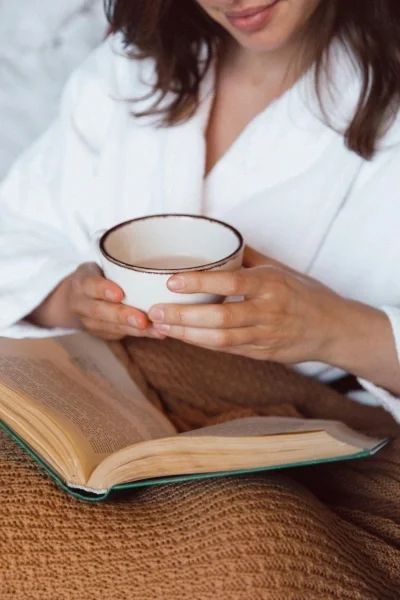 Woman with coffee mug and book