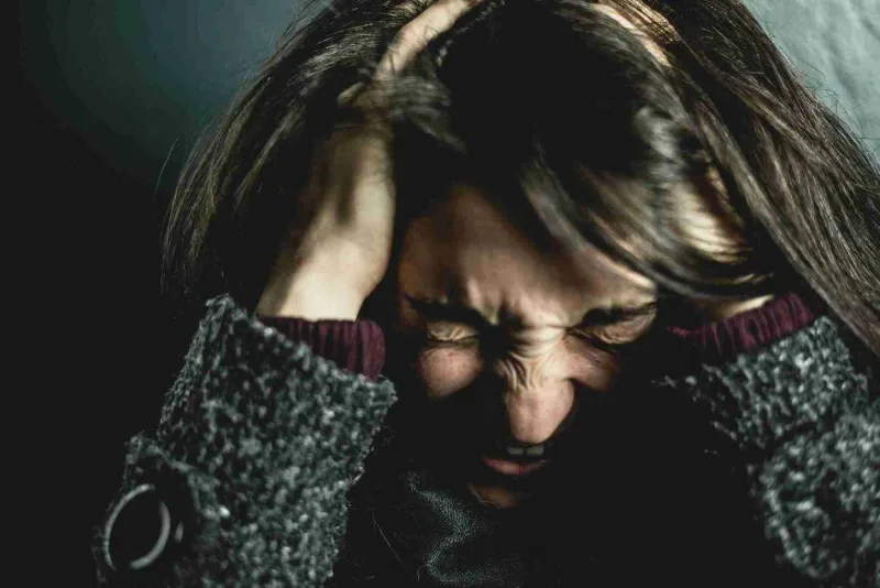 Woman holding her head grimacing