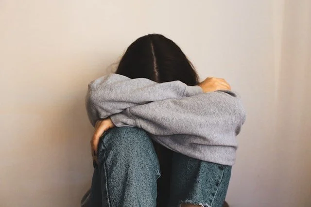 woman-sitting-on-the-floor-with-her-arms-wrapped-around-her-head