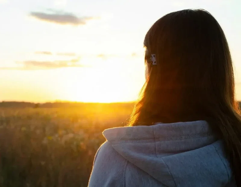 Woman facing away towards a sunset