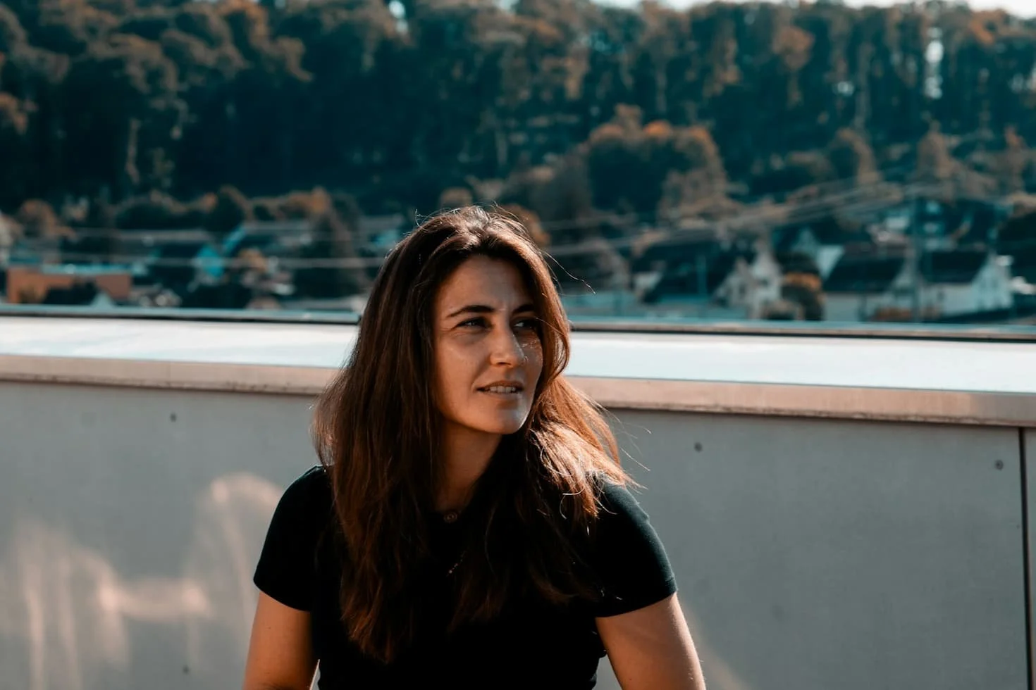 a-woman-sitting-on-a-ledge-with-a-city-in-the-background