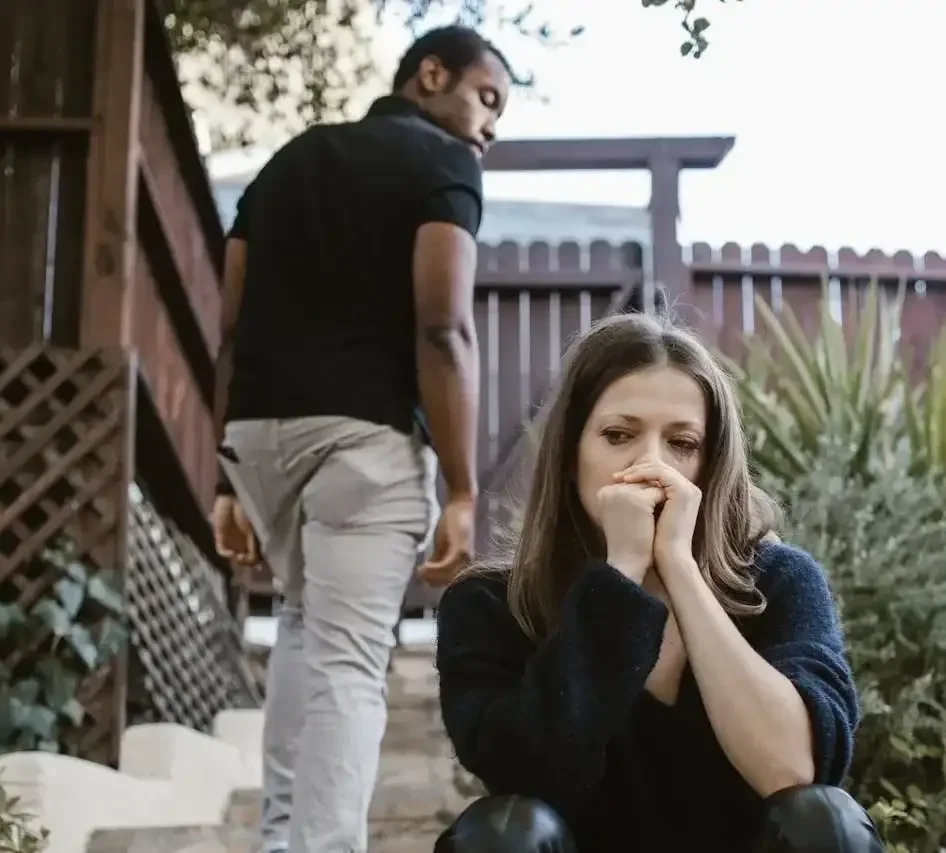 Woman sitting on outdoor steps with hands on face while man walks away glancing back
