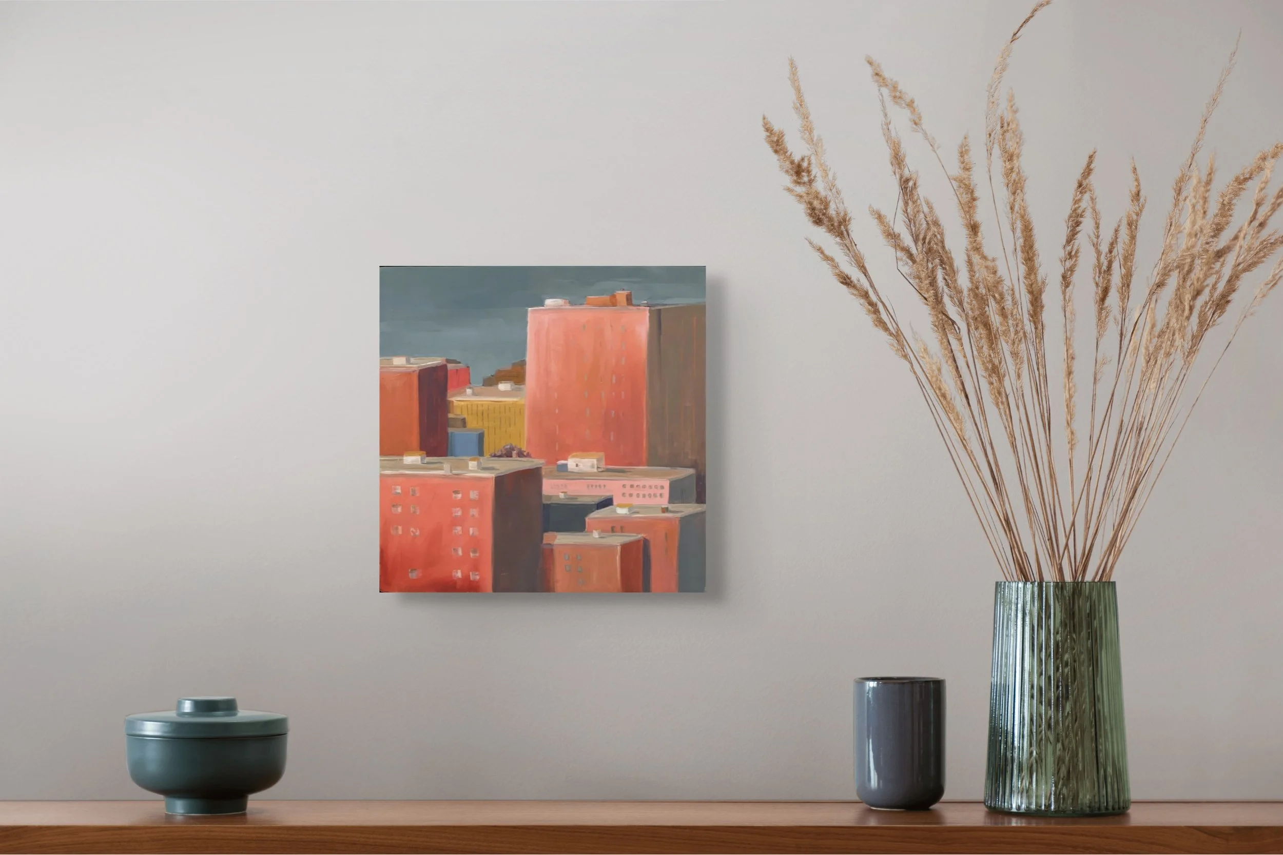 Cityscape oil painting on wood panel, titled ‘Fragment of a City I,’ shown hanging on a wall above a chest, by artist Fabienne Herbert