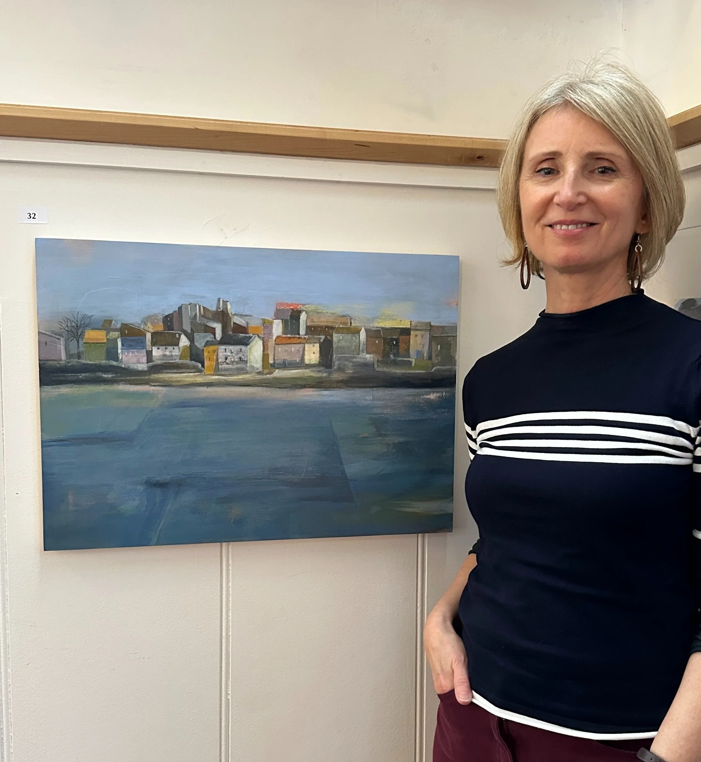 Acrylic painting of village and water with artist Fabienne