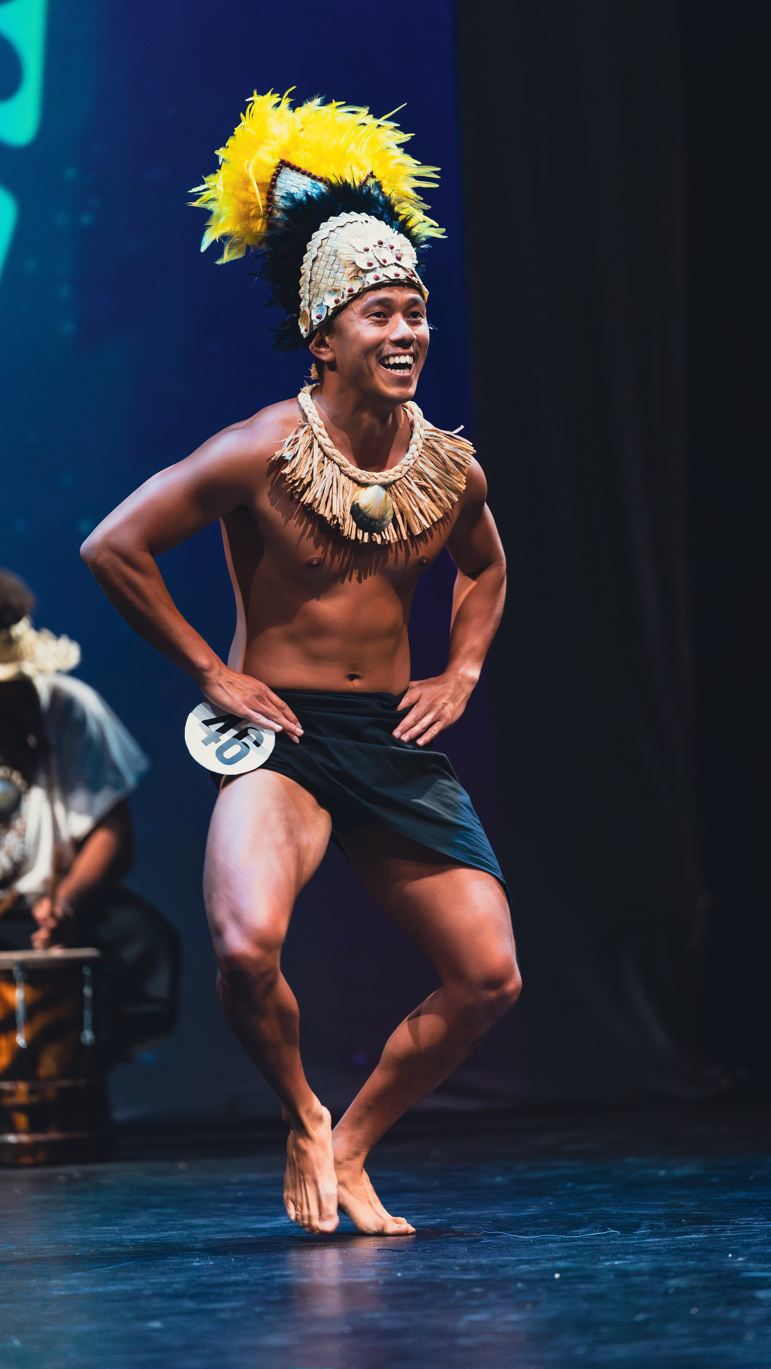 Man in traditional Polynesian attire performing a cultural dance on stage.