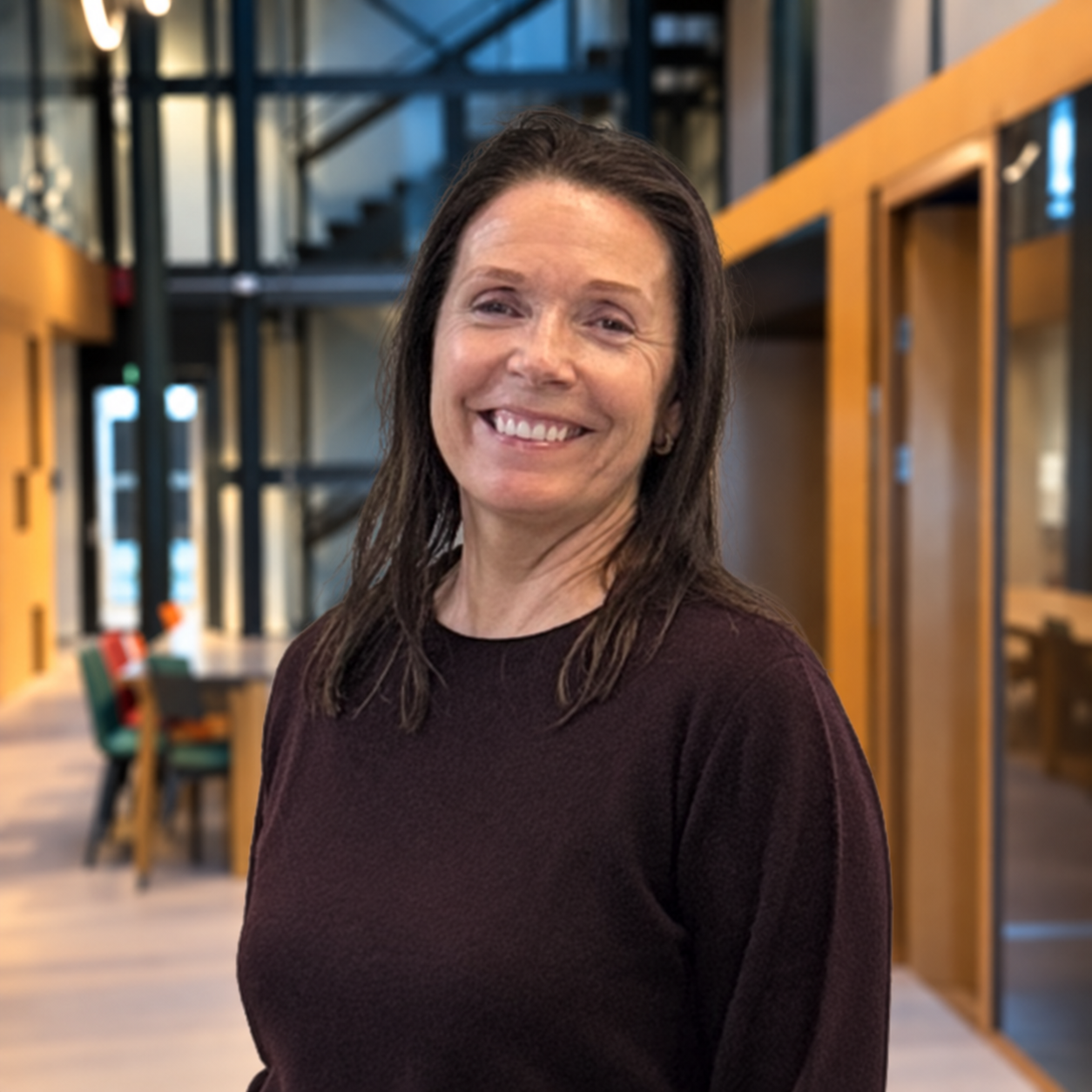 En kvinne med mørkt hår smiler i et innendørs miljø, iført en hvit polo-shirt med tekst på venstre side som sier 'HOUSE of HEALTH' og 'DR. ELISABETH RØDLAND' på høyre side.