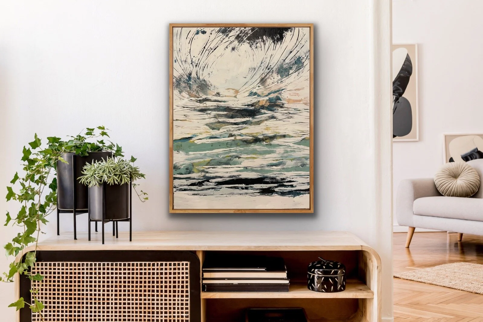 Living room interior with abstract landscape painting, potted ivy and succulent on a console, cream sofa with round pillow, artwork on walls, wooden floor.