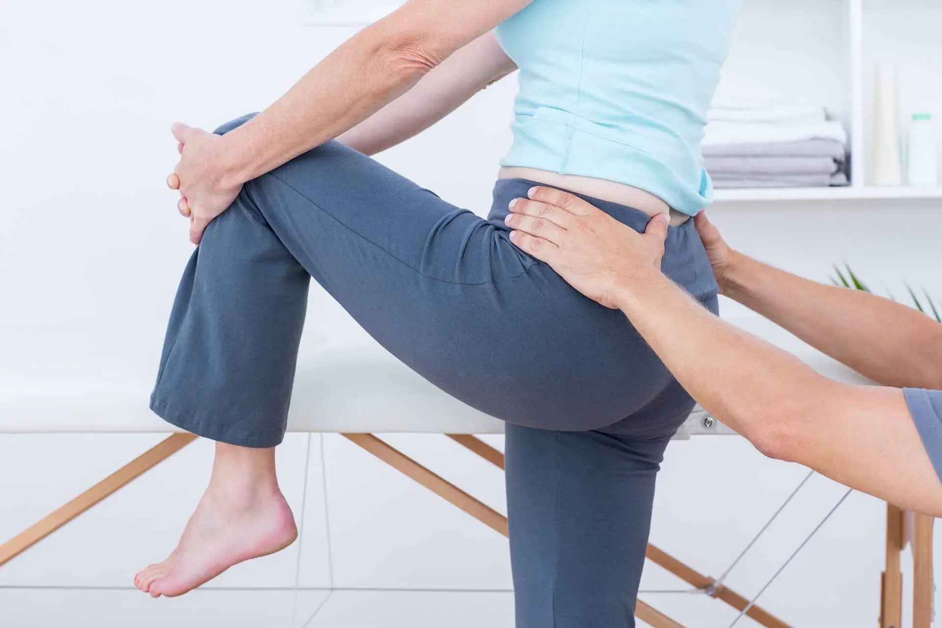 Physiotherapist assessing hip stiffness and lower back pain in a patient during treatment.