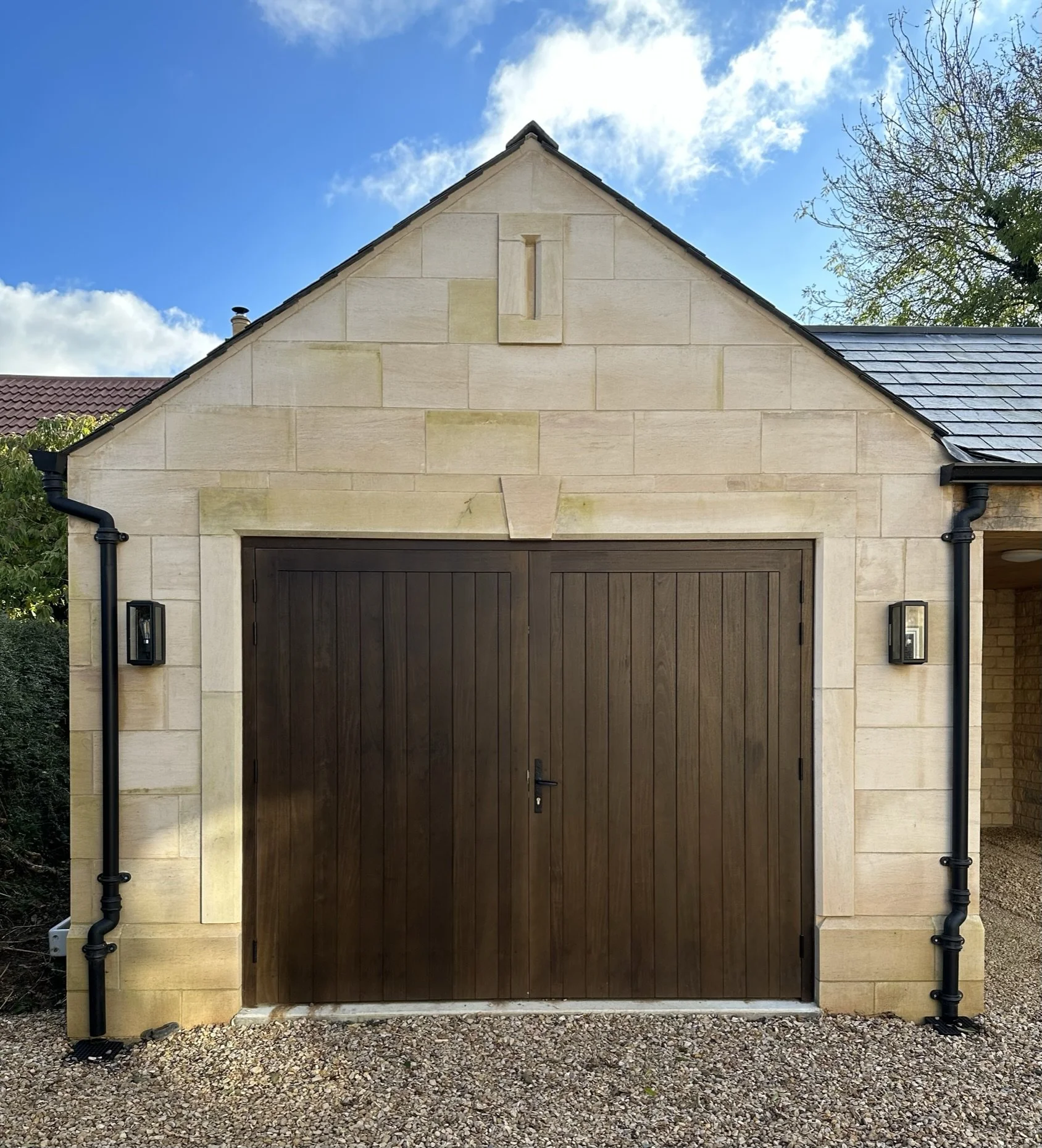 Bespoke idigbo dark walnut stain garage doors with black hardware.