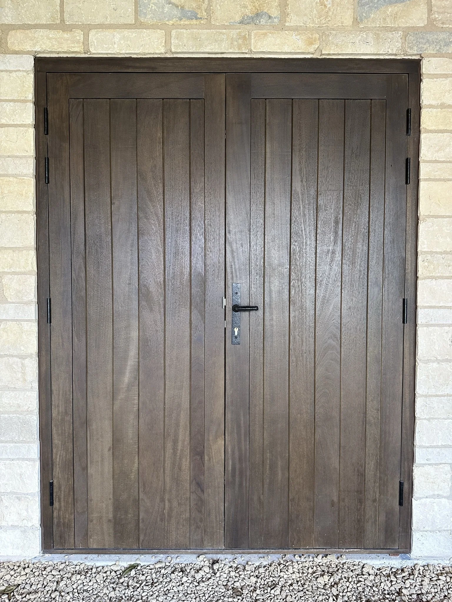 Bespoke idigbo timber, walnut stain garage doors with black hardware.
