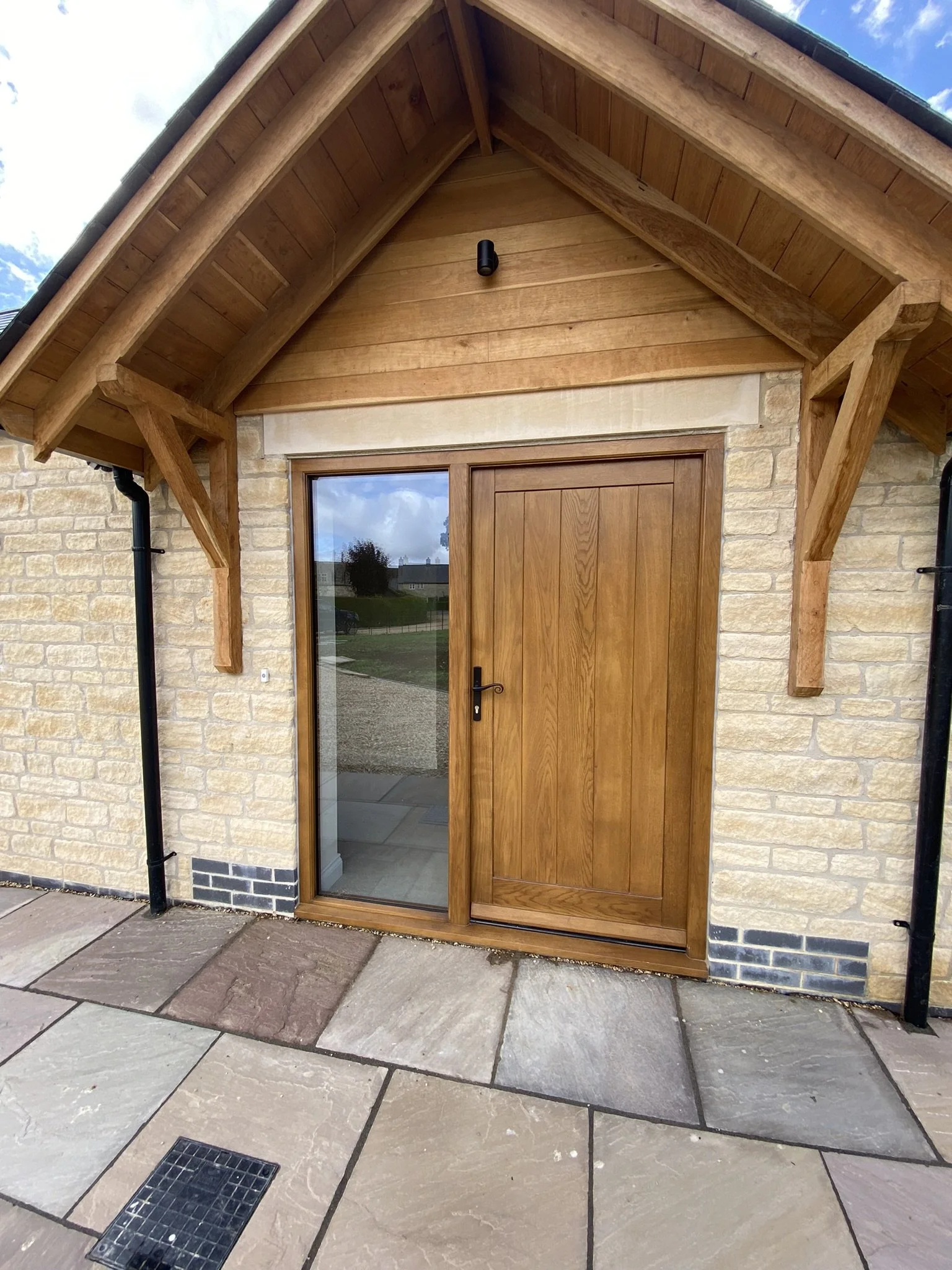 Tongue and groove paneled high performance oak door and frame with black hardware and fully glazed side light 