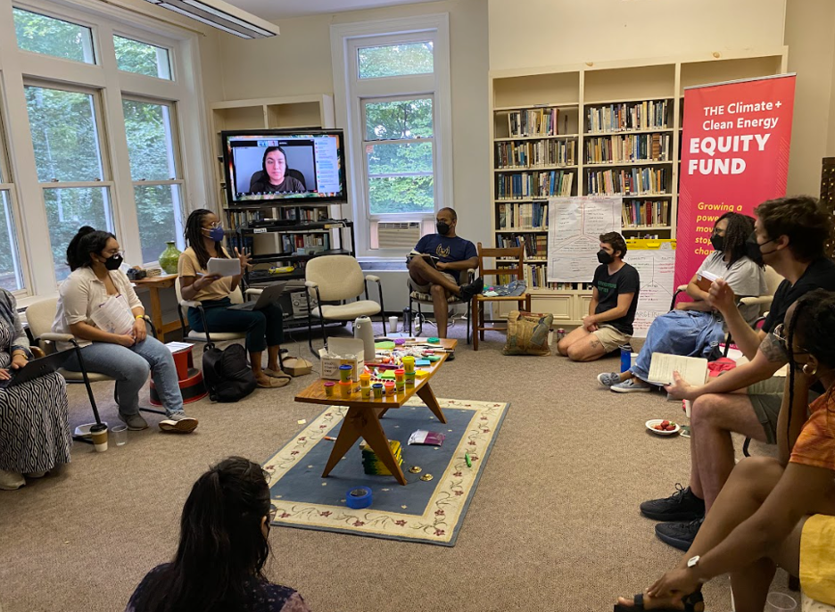    Fellows sit in a circle listening to Carolina Ortiz (Associate Executive Director of COPAL MN) discuss the topic of setting policy goals.   