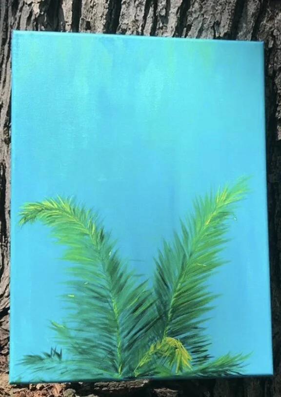 Painting of green palm leaves on a bright blue background, propped against a tree trunk.